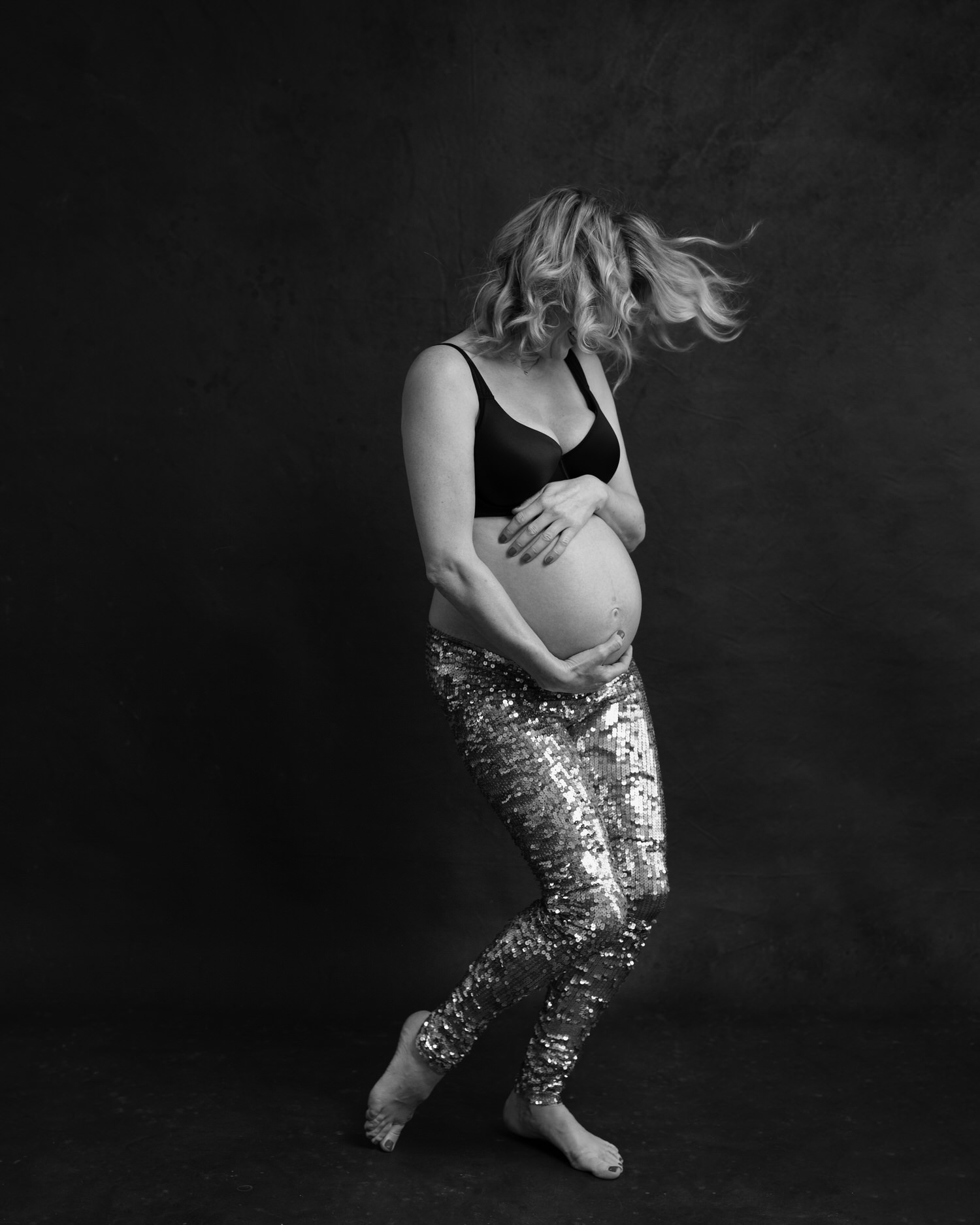 Happy pregnant woman dancing in Toronto photography studio.