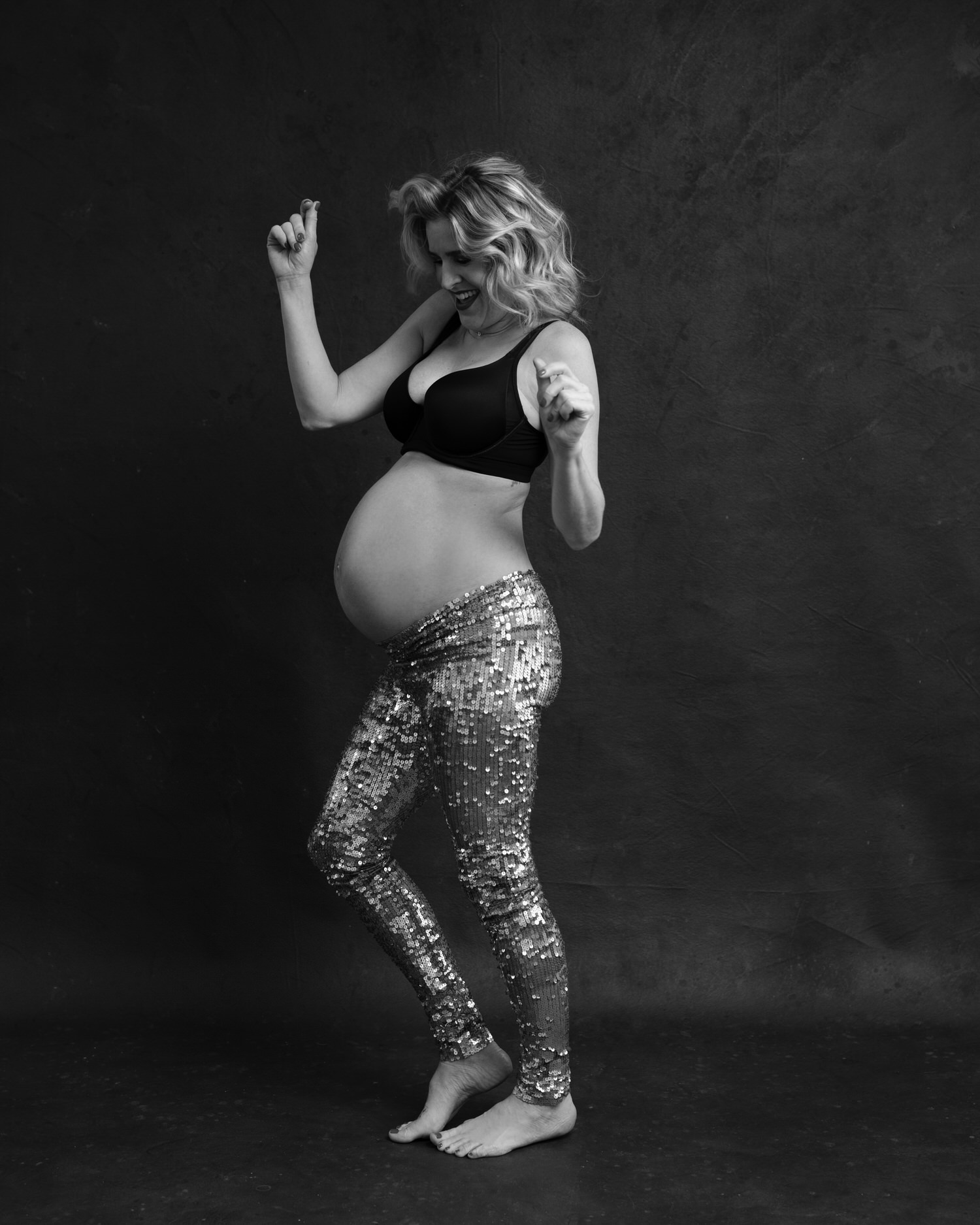 Happy pregnant woman dancing in Toronto photography studio.