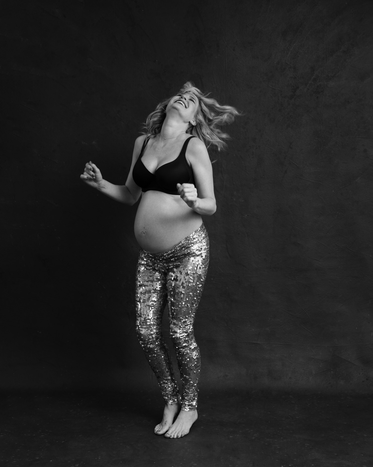 Happy pregnant woman dancing in Toronto photography studio.