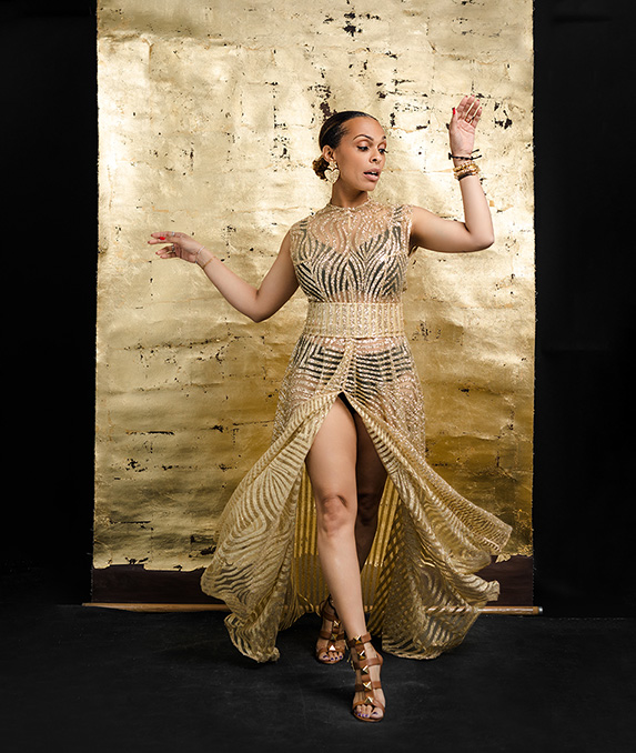 Powerful and feminine portrait of a woman wearing gold dress against a gold backdrop