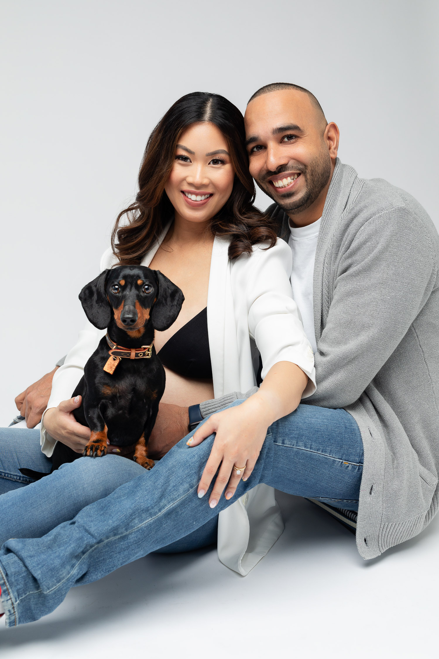Couple with a dog posing for a maternity photoshoot
